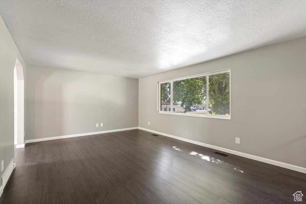 Empty room with a textured ceiling and wood-type flooring