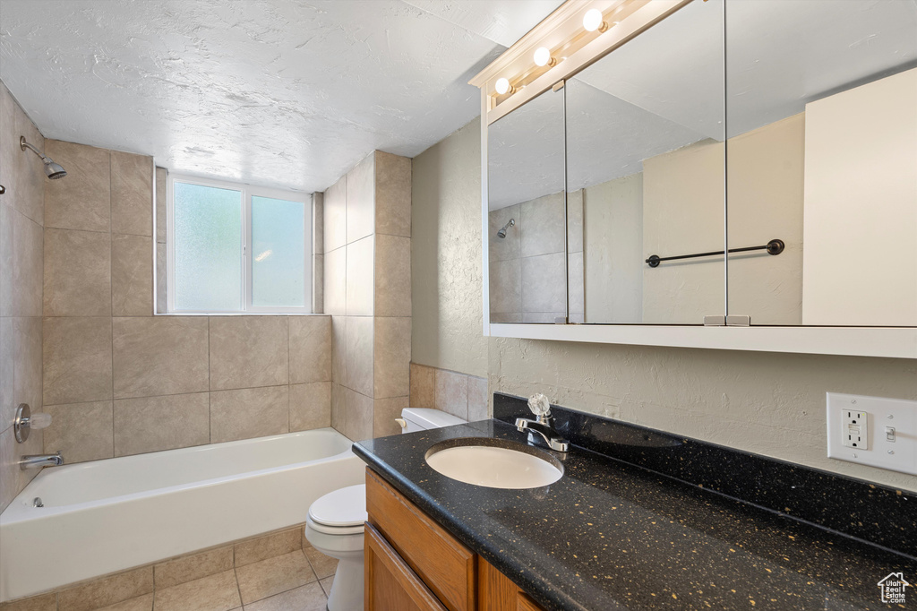 Full bathroom with tiled shower / bath combo, toilet, and tile patterned floors