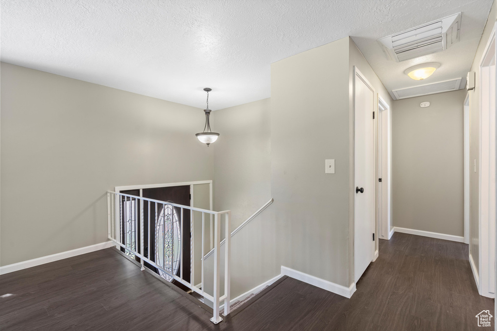 Hall featuring a textured ceiling and dark wood-type flooring