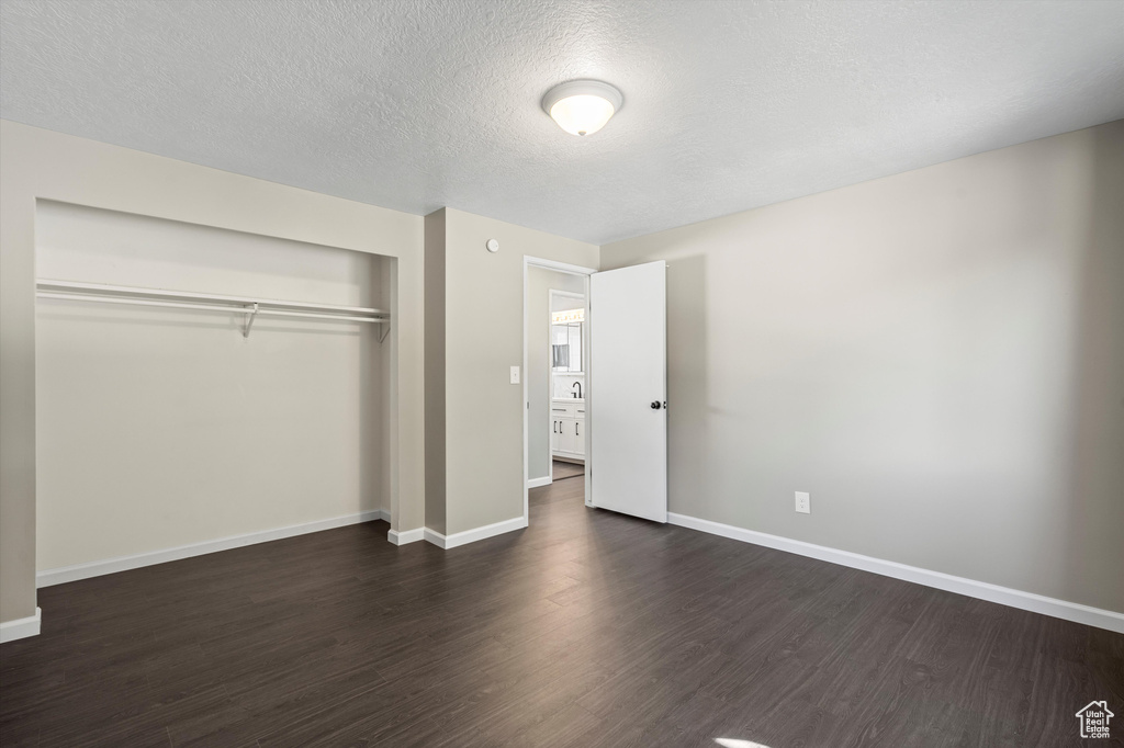 Unfurnished bedroom featuring dark hardwood / wood-style flooring, a closet, and a textured ceiling