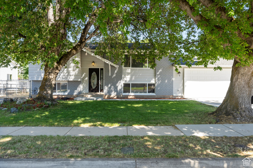 Bi-level home featuring a garage and a front lawn