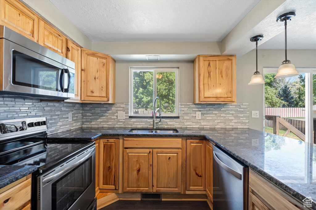 Kitchen with sink, a wealth of natural light, tasteful backsplash, and stainless steel appliances