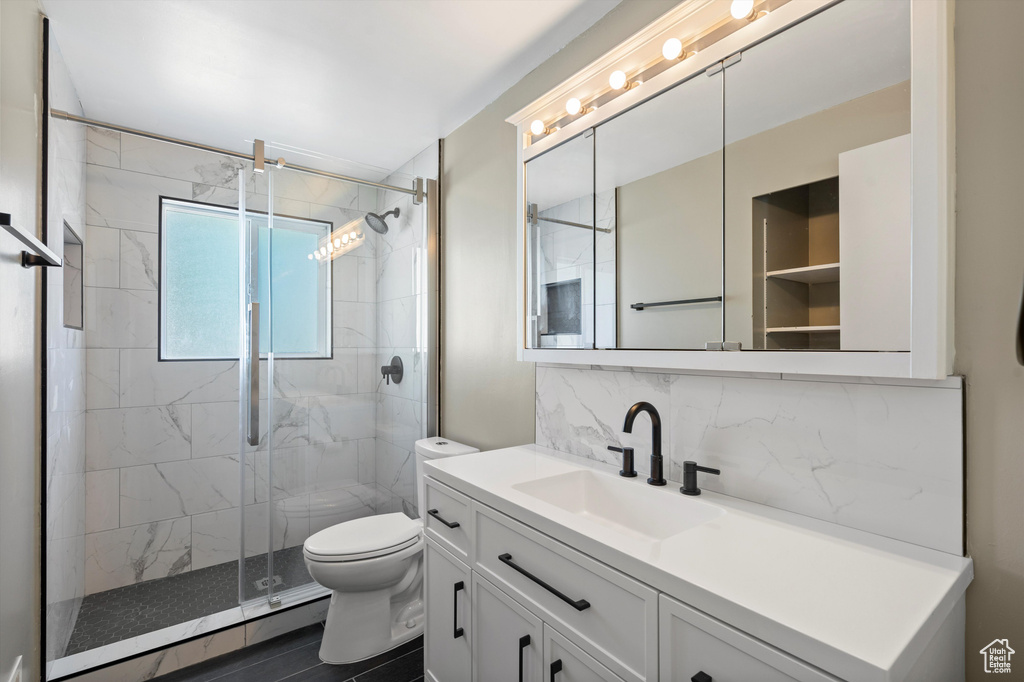 Bathroom with vanity, tile walls, toilet, a shower with door, and backsplash