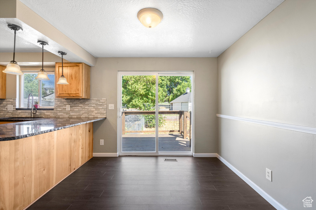 Kitchen featuring decorative backsplash, hanging light fixtures, sink, and plenty of natural light