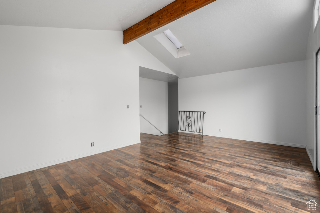 Spare room featuring lofted ceiling with skylight and dark wood-type flooring