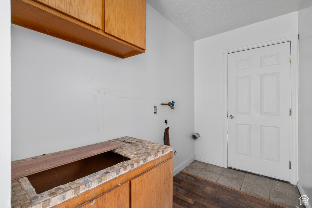 Clothes washing area featuring cabinets, hookup for an electric dryer, dark hardwood / wood-style floors, hookup for a washing machine, and a textured ceiling