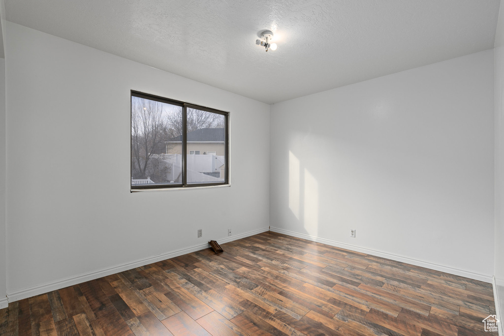Unfurnished room with a textured ceiling and dark wood-type flooring