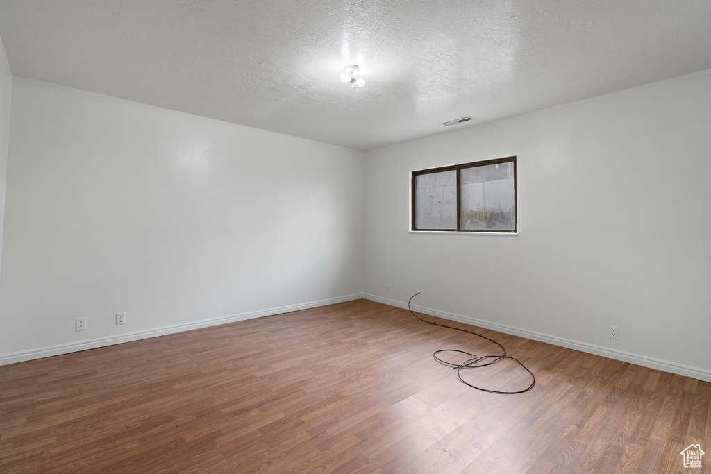Spare room featuring a textured ceiling and hardwood / wood-style flooring