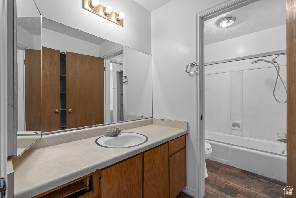 Full bathroom featuring hardwood / wood-style floors, vanity, toilet, and shower / bath combination