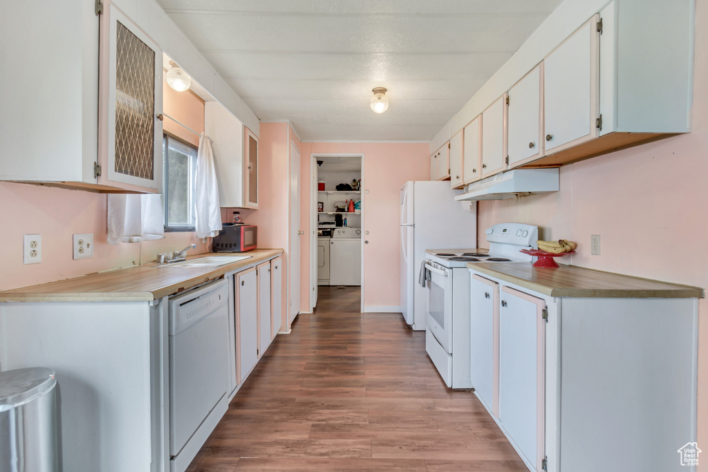 Kitchen with white appliances, white cabinets, sink, independent washer and dryer, and wood-type flooring