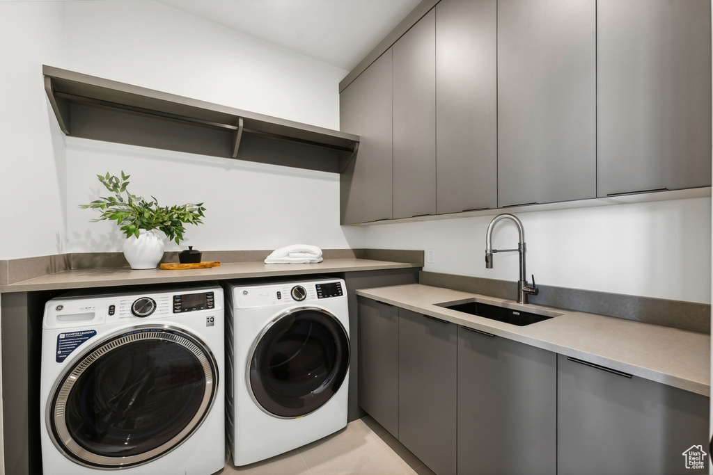 Laundry area featuring cabinets, washing machine and clothes dryer, light tile patterned floors, and sink