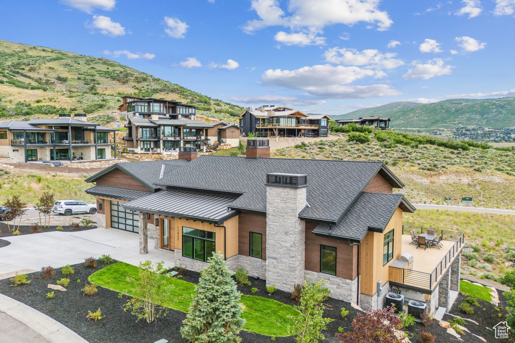 View of front of property with a mountain view, a balcony, and cooling unit