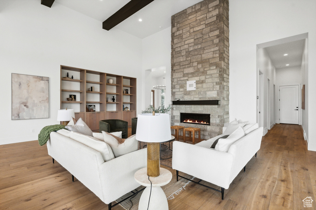 Living room featuring a stone fireplace, hardwood / wood-style floors, and a towering ceiling