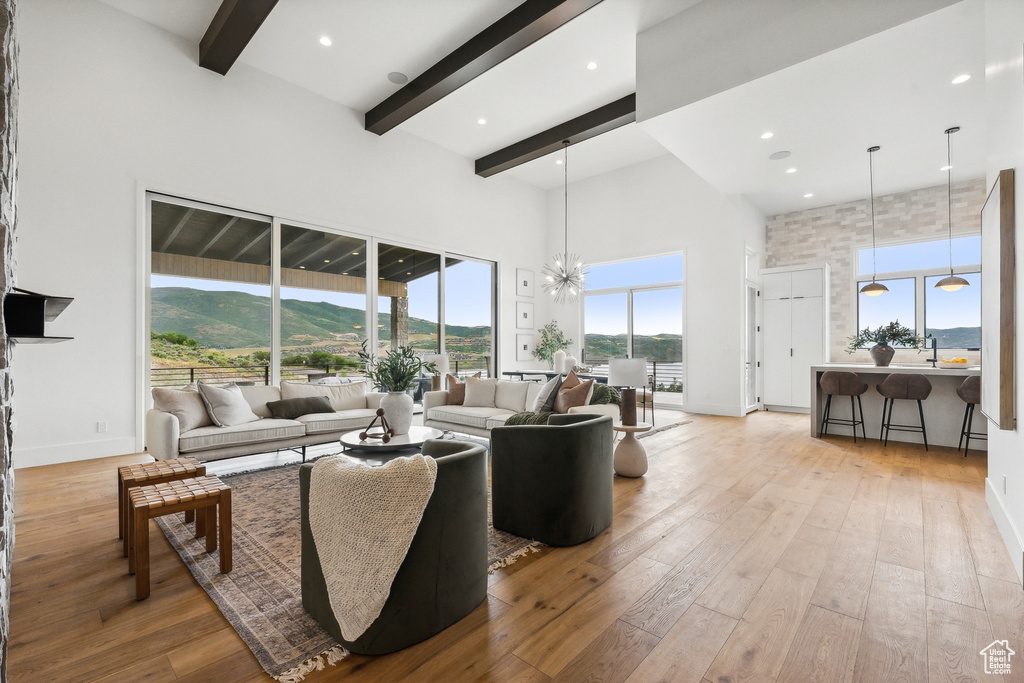 Living room with a notable chandelier, a mountain view, light wood-type flooring, and a high ceiling