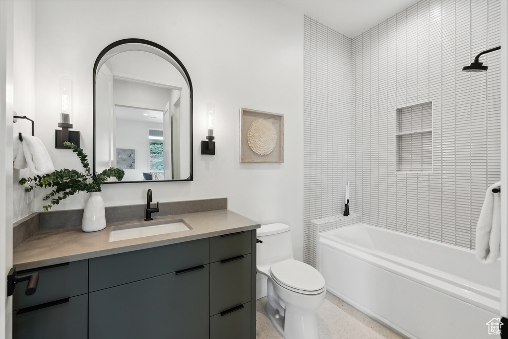 Full bathroom featuring vanity, tiled shower / bath combo, and toilet