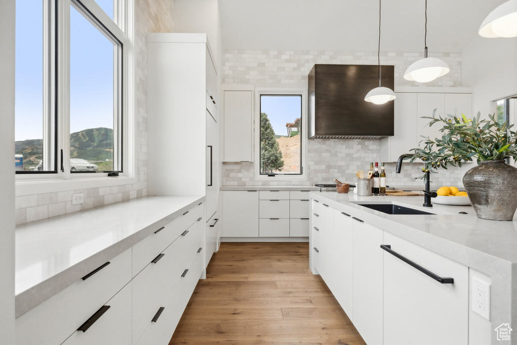 Kitchen with sink, light wood-type flooring, tasteful backsplash, and decorative light fixtures