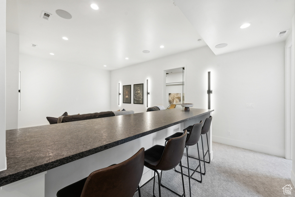 Kitchen featuring light carpet and a breakfast bar