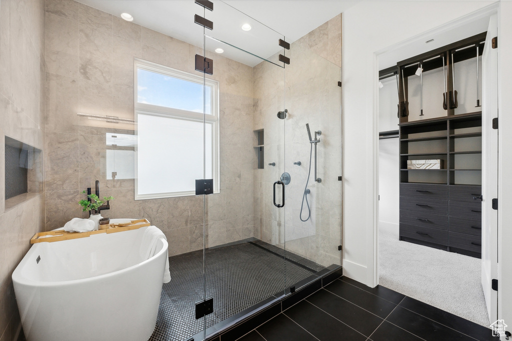 Bathroom with tile patterned flooring, tile walls, and plus walk in shower