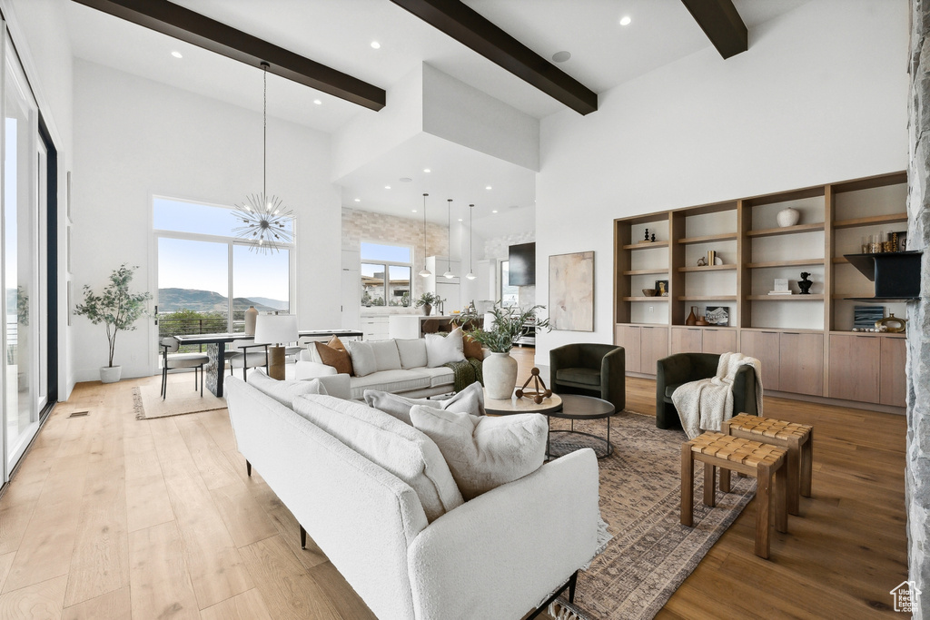 Living room with a notable chandelier, light hardwood / wood-style flooring, and a high ceiling