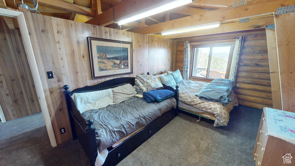 Bedroom featuring wooden walls, carpet flooring, and beam ceiling