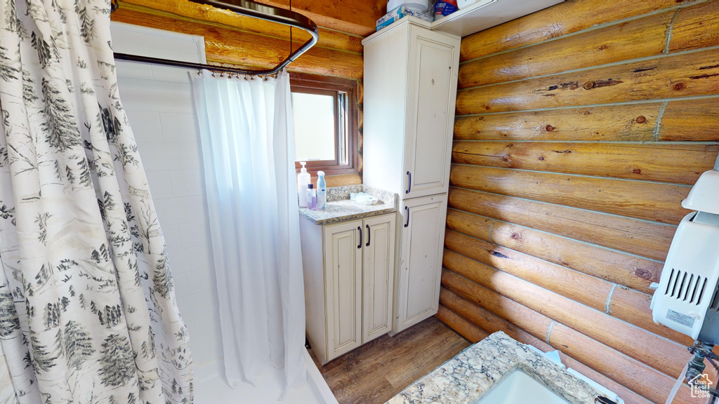 Bathroom with vanity, hardwood / wood-style flooring, and log walls