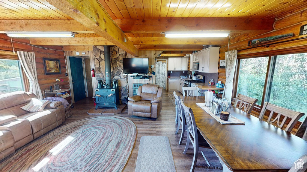 Living room featuring wooden ceiling, a wood stove, beam ceiling, and hardwood / wood-style floors