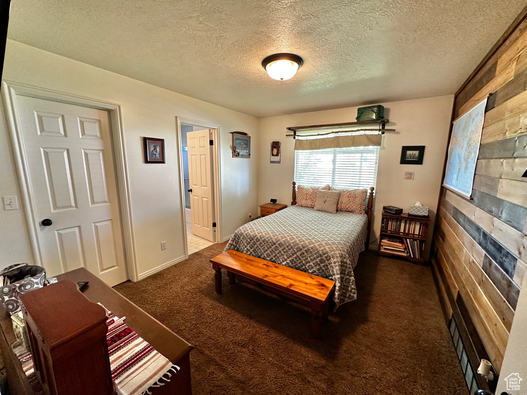 Bedroom with dark carpet and a textured ceiling