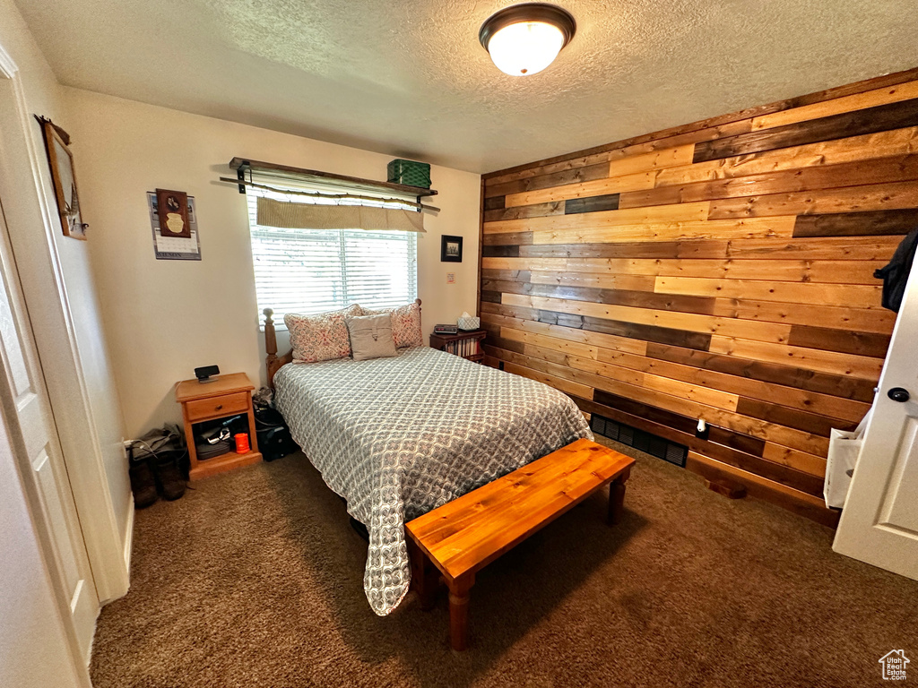 Carpeted bedroom with a textured ceiling and wooden walls