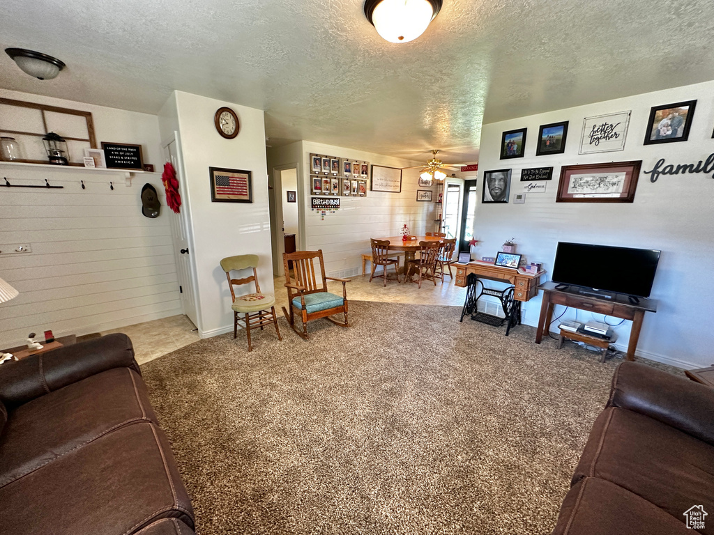 Living room featuring ceiling fan, carpet flooring, and a textured ceiling