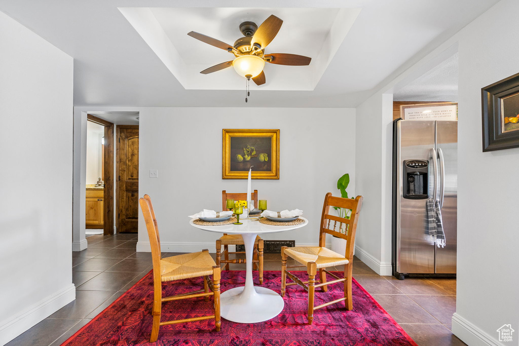 Dining area featuring a tray ceiling, tile patterned flooring, and ceiling fan