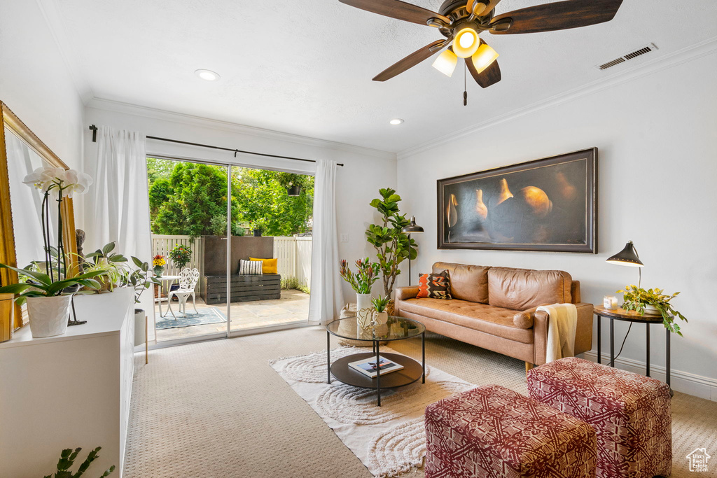 Carpeted living room with ornamental molding and ceiling fan