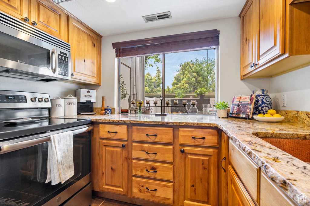 Kitchen with light stone counters and stainless steel appliances