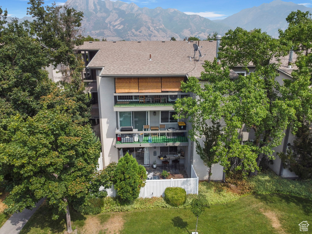 Back of property with a mountain view, a balcony, and a lawn