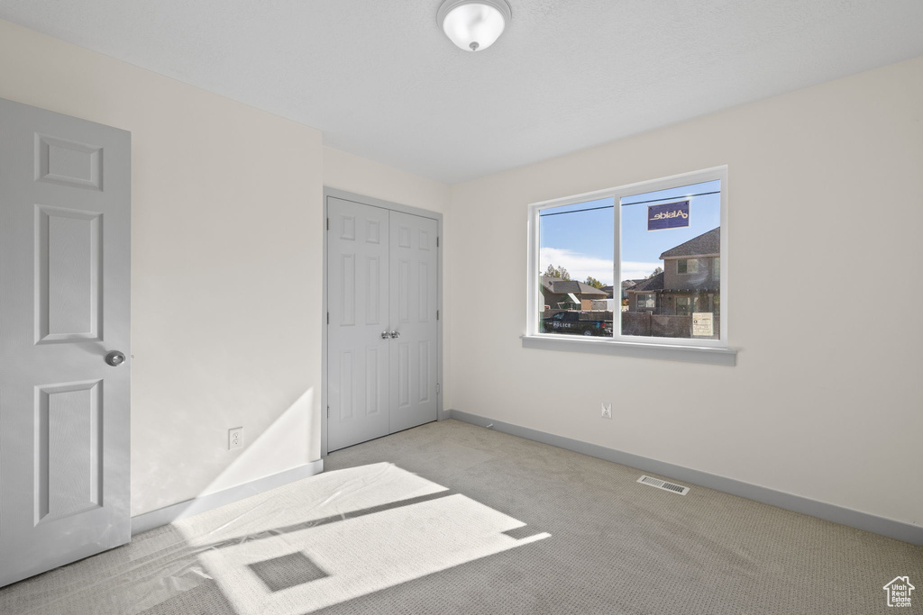 Unfurnished bedroom featuring light carpet and a closet