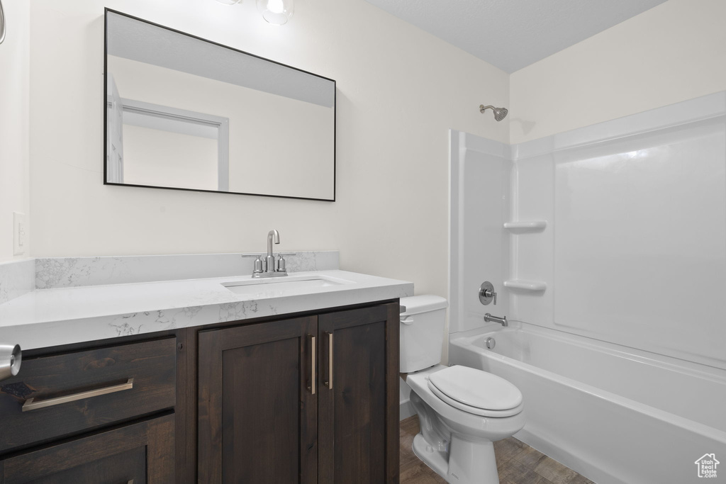 Full bathroom with vanity, hardwood / wood-style floors, toilet, and shower / bath combination