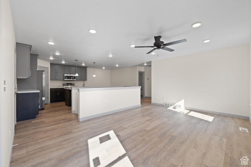 Unfurnished living room featuring light wood-type flooring and ceiling fan