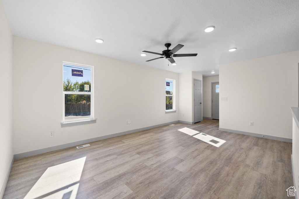 Spare room with a wealth of natural light, light hardwood / wood-style flooring, a textured ceiling, and ceiling fan