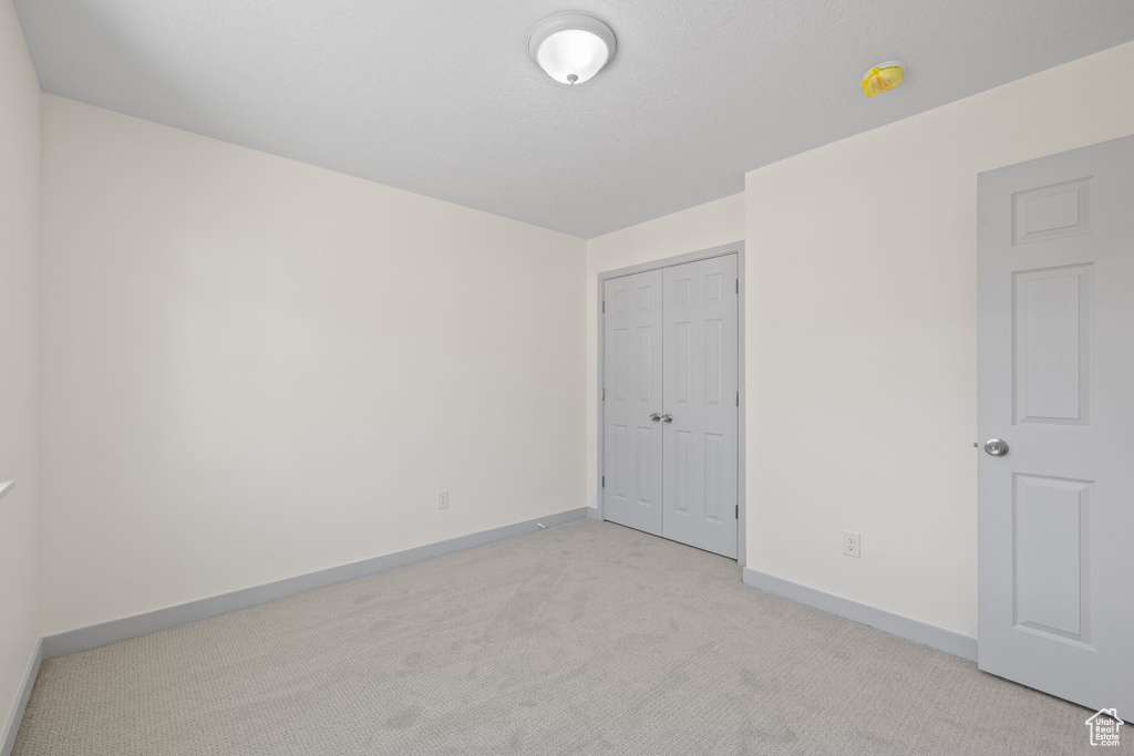 Unfurnished bedroom featuring a closet and light colored carpet