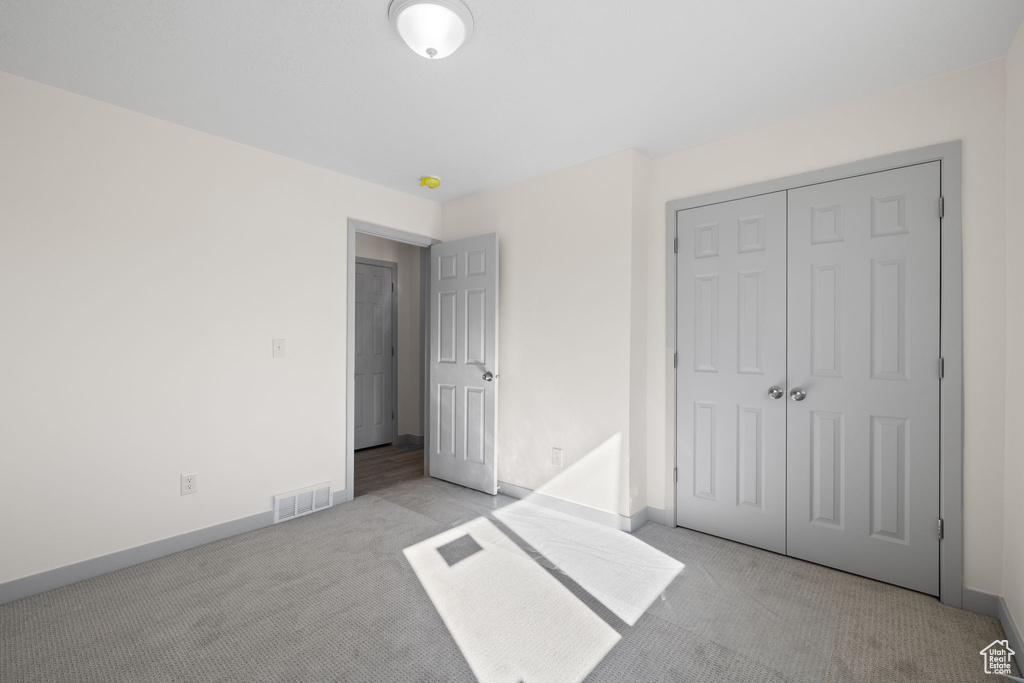 Unfurnished bedroom featuring a closet and light colored carpet