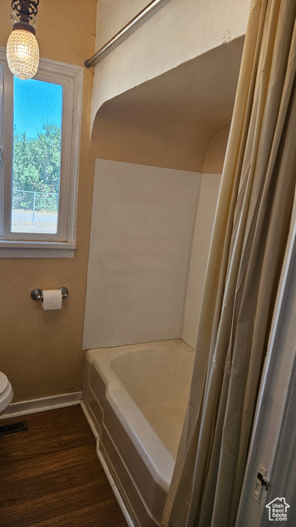 Bathroom featuring shower / bath combo with shower curtain, toilet, and hardwood / wood-style flooring