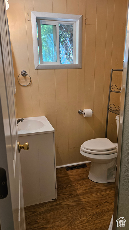 Bathroom with wooden walls, vanity, hardwood / wood-style flooring, and toilet