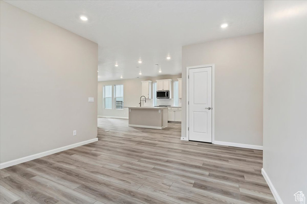 Unfurnished living room with light hardwood / wood-style floors and sink