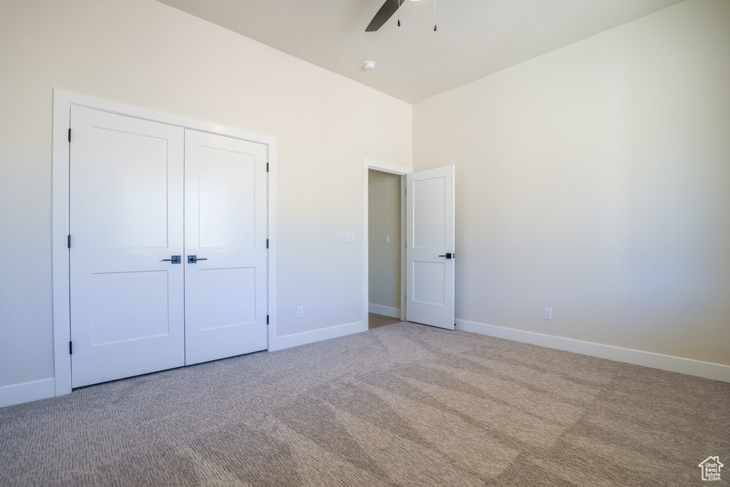 Unfurnished bedroom with ceiling fan, light colored carpet, and a closet