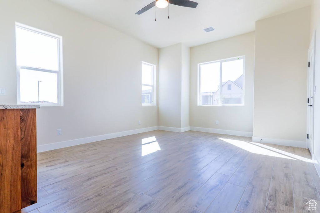 Empty room with light hardwood / wood-style floors and ceiling fan