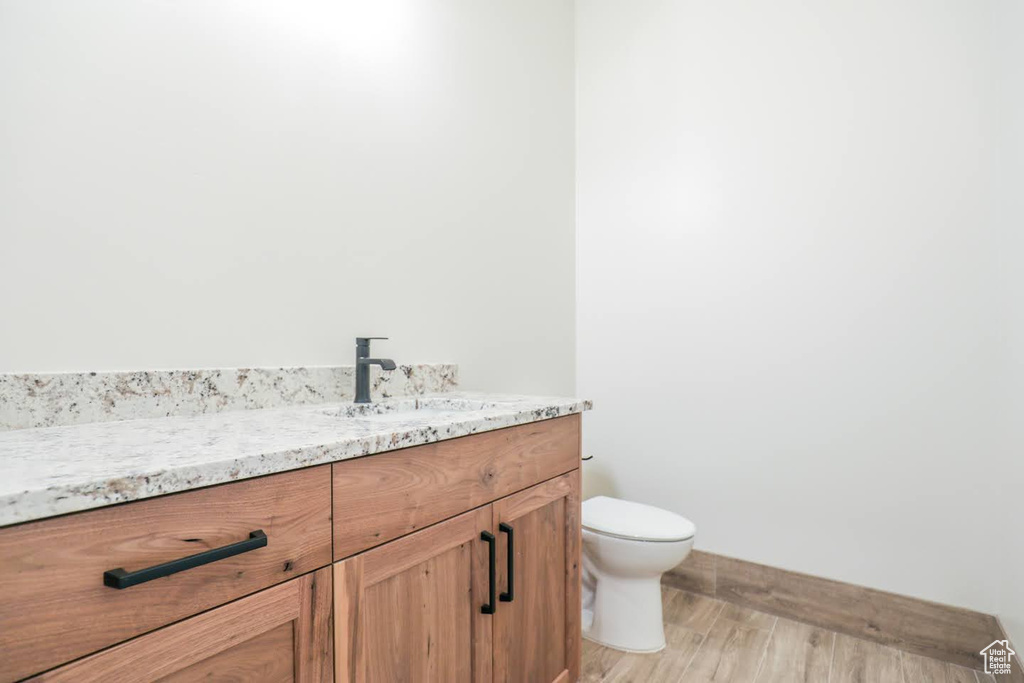 Bathroom featuring hardwood / wood-style floors, vanity, and toilet