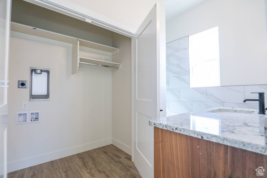 Interior space with hookup for a washing machine, dark hardwood / wood-style floors, sink, and hookup for an electric dryer