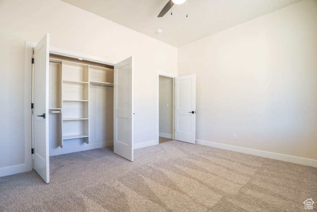 Unfurnished bedroom with ceiling fan, light colored carpet, and a closet