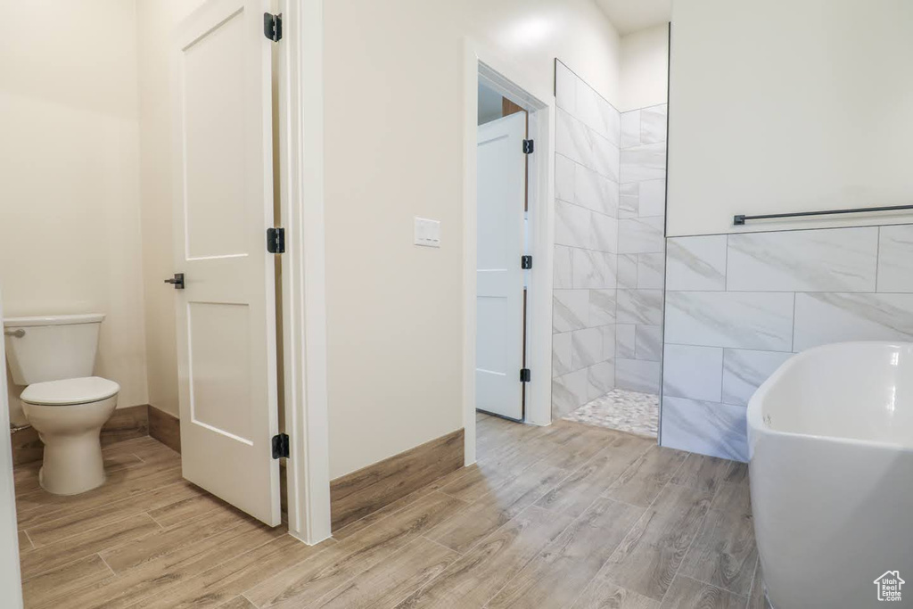 Bathroom featuring separate shower and tub, tile walls, toilet, and hardwood / wood-style flooring