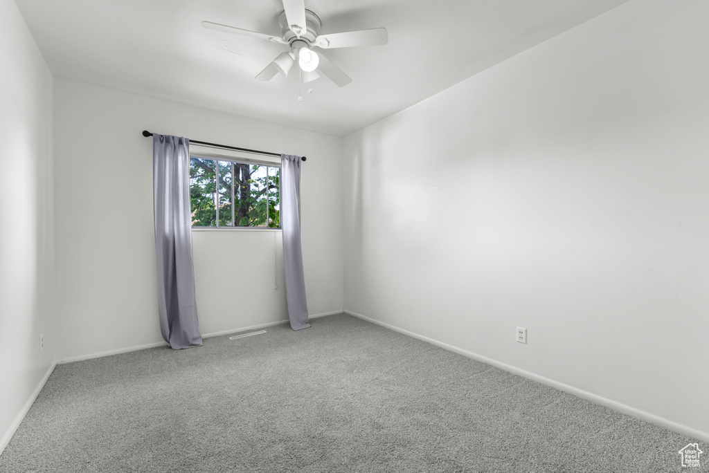 Carpeted spare room featuring ceiling fan