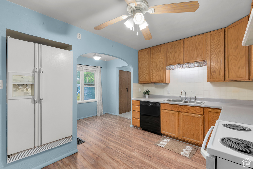 Kitchen featuring ceiling fan, white appliances, sink, light hardwood / wood-style floors, and backsplash